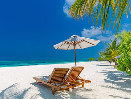 two lounge chairs under umbrella on shoreline