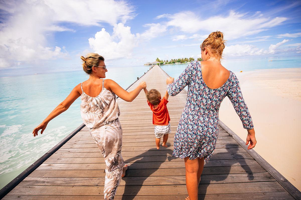 A lesbian couple and their child walk along a pier