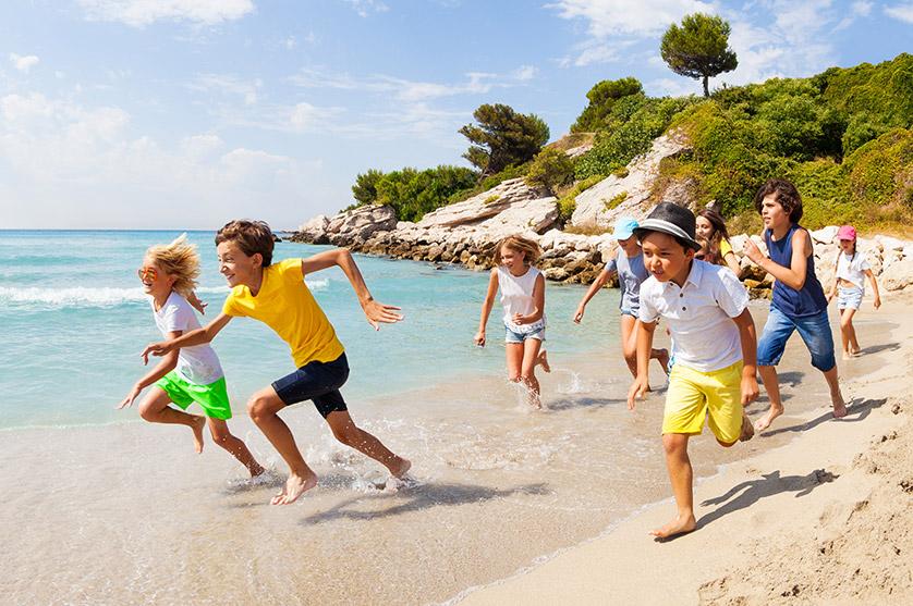 A group of kids run on a beach